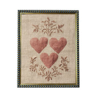 a framed piece of artwork with a beige background and a border. The artwork is a close-up of three red hearts arranged in a triangular formation, surrounded by a floral design.