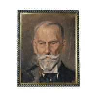 The image is a portrait of an elderly man with a white beard and mustache, wearing a suit and tie.