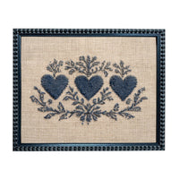 a framed embroidered design with three blue hearts and floral elements.
