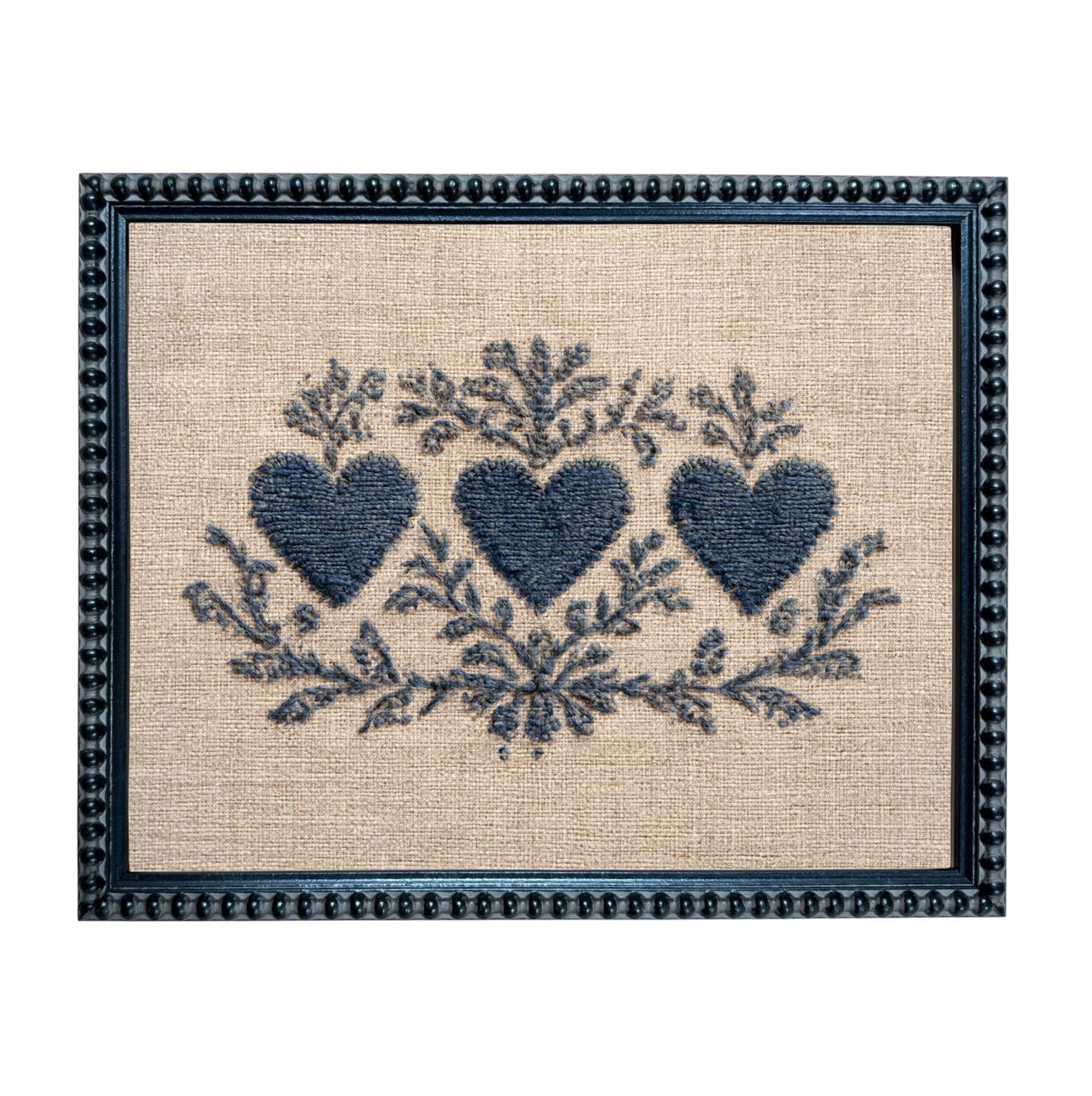 a framed embroidered design with three blue hearts and floral elements.