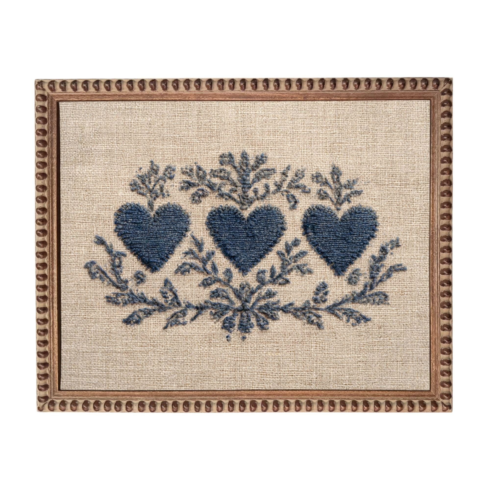 a square frame with a beige background and a decorative border. The frame contains a blue floral design with three blue hearts arranged in a symmetrical pattern.