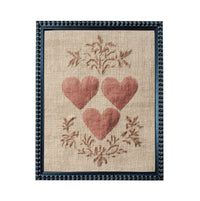 a framed piece of artwork with a beige background and a floral design. The artwork is framed in a black frame with a decorative border. The artwork displays three red hearts arranged in a circular pattern, surrounded by a floral design.