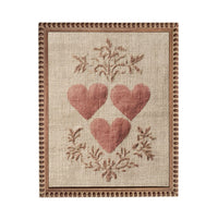 a beige fabric with a decorative border and three red heart-shaped embroidered designs.